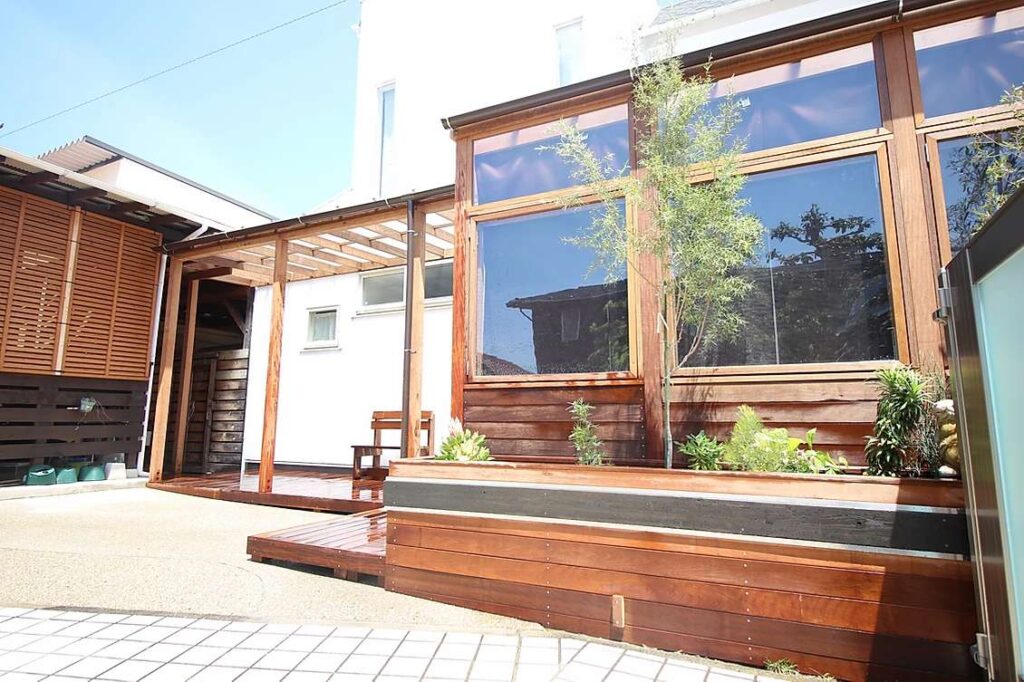 ガーデンルームで庭にくつろぎの空間を取り入れた事例。木製の特注ガーデンルームで庭と一体化できます。