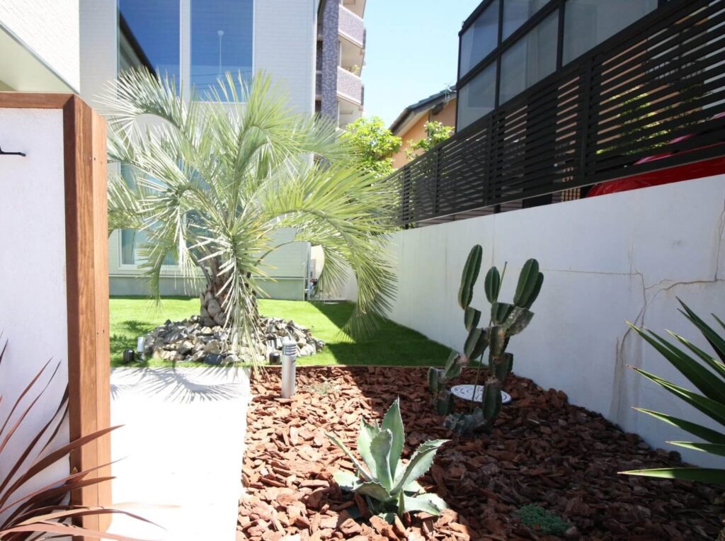 リゾート感のある洋風オシャレ外構。白い門柱とウッドチップを組み合わせた植栽で高級感の演出。